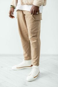 Catalogue fashion studio shoot. Man legs in cargo trousers. Trendy beige outfit.