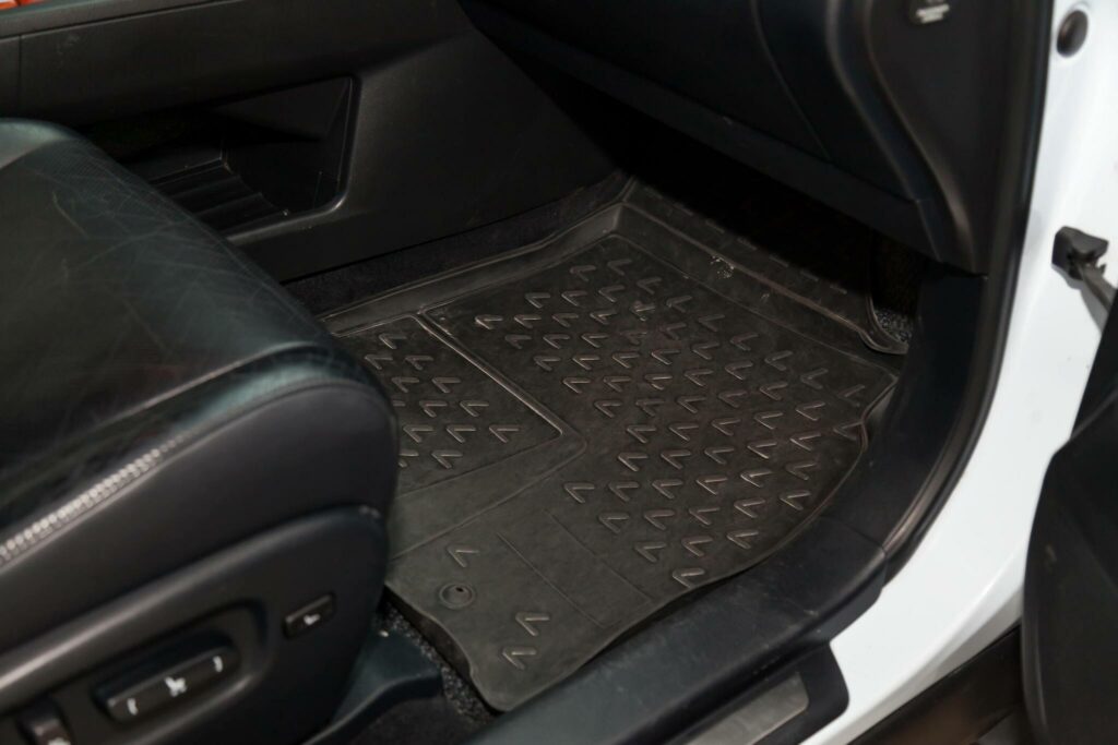 Novosibirsk, Russia - 12.19.2019: Dirty car floor mats of black rubber under passenger seat in the workshop for the detailing vehicle before dry cleaning. Auto service industry. Interior of sedan.