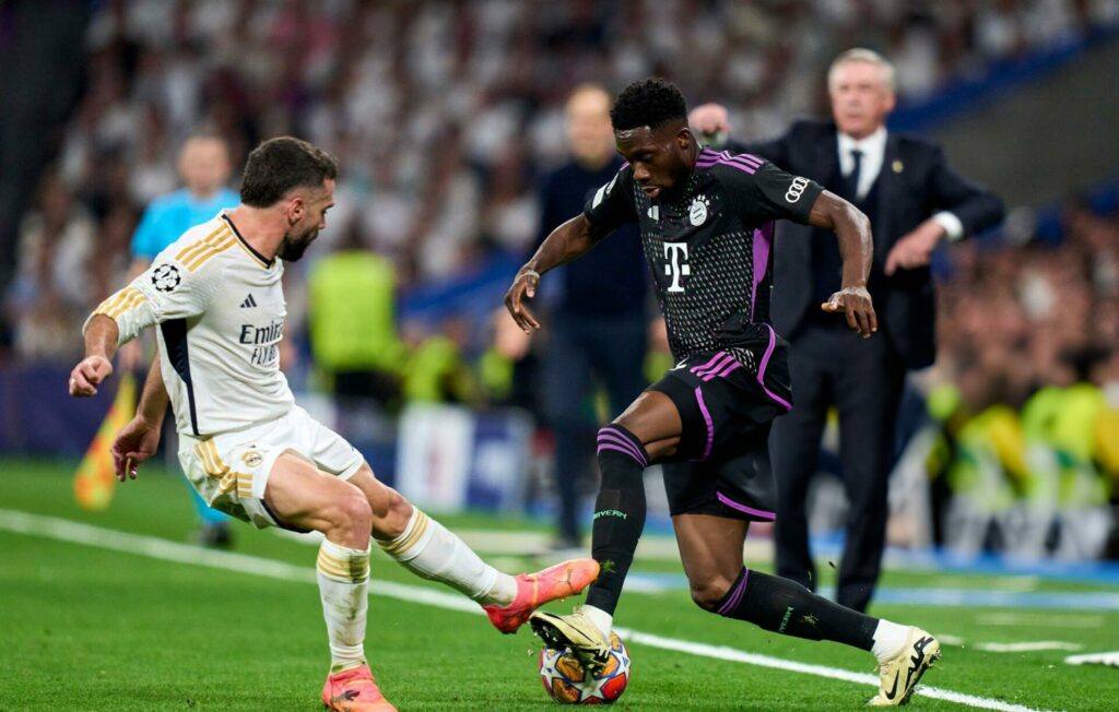 MADRID, SPAIN - MAY 08: Alphonso Davies of FC Bayern Munchen dribbles the ball against Dani Carvajal of Real Madrid during the UEFA Champions League semi-final second-leg match between Real Madrid and FC Bayern München at Estadio Santiago Bernabeu on May 08, 2024 in Madrid, Spain. (Photo by Diego Souto/Getty Images)