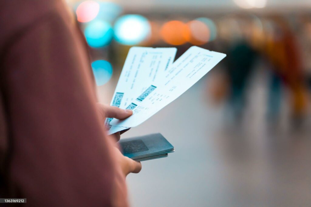 A young girl is going on a trip, holds plane tickets in her hands and goes to check-in, boarding a flight, close-up view of a boarding pass on a blurred background.