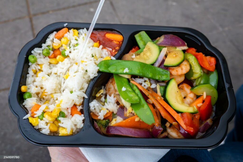 Vienna, Austria Stir fry vegetables and shrimp take-out with rice in a plastic container.